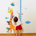 Criança alcançando régua de altura na parede