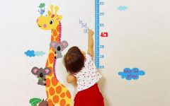 Criança alcançando régua de altura na parede